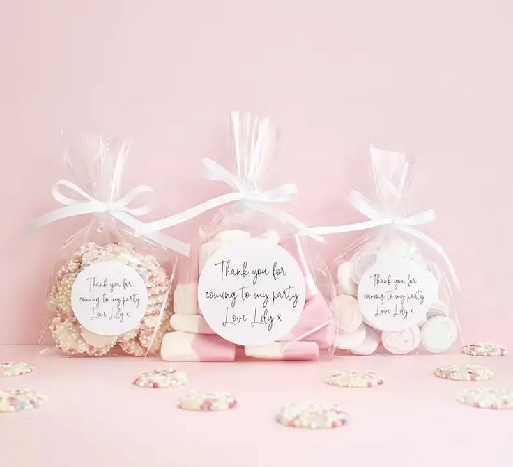 three bags filled with cookies sitting on top of a pink table next to each other