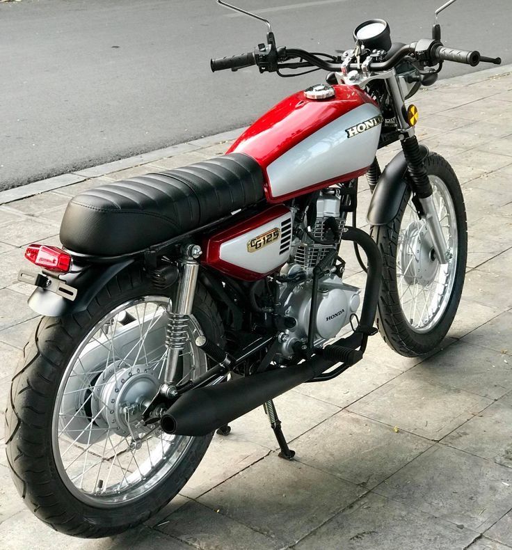 a red and white motorcycle parked on the sidewalk