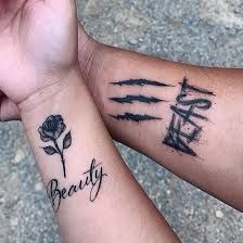 two people holding hands with tattoos on their arms that say beauty and the word love written in cursive writing