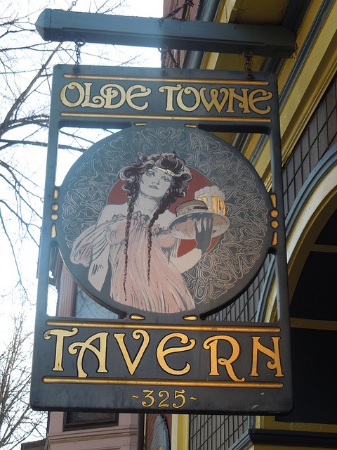 a sign for an olde town tavern hanging from the side of a building