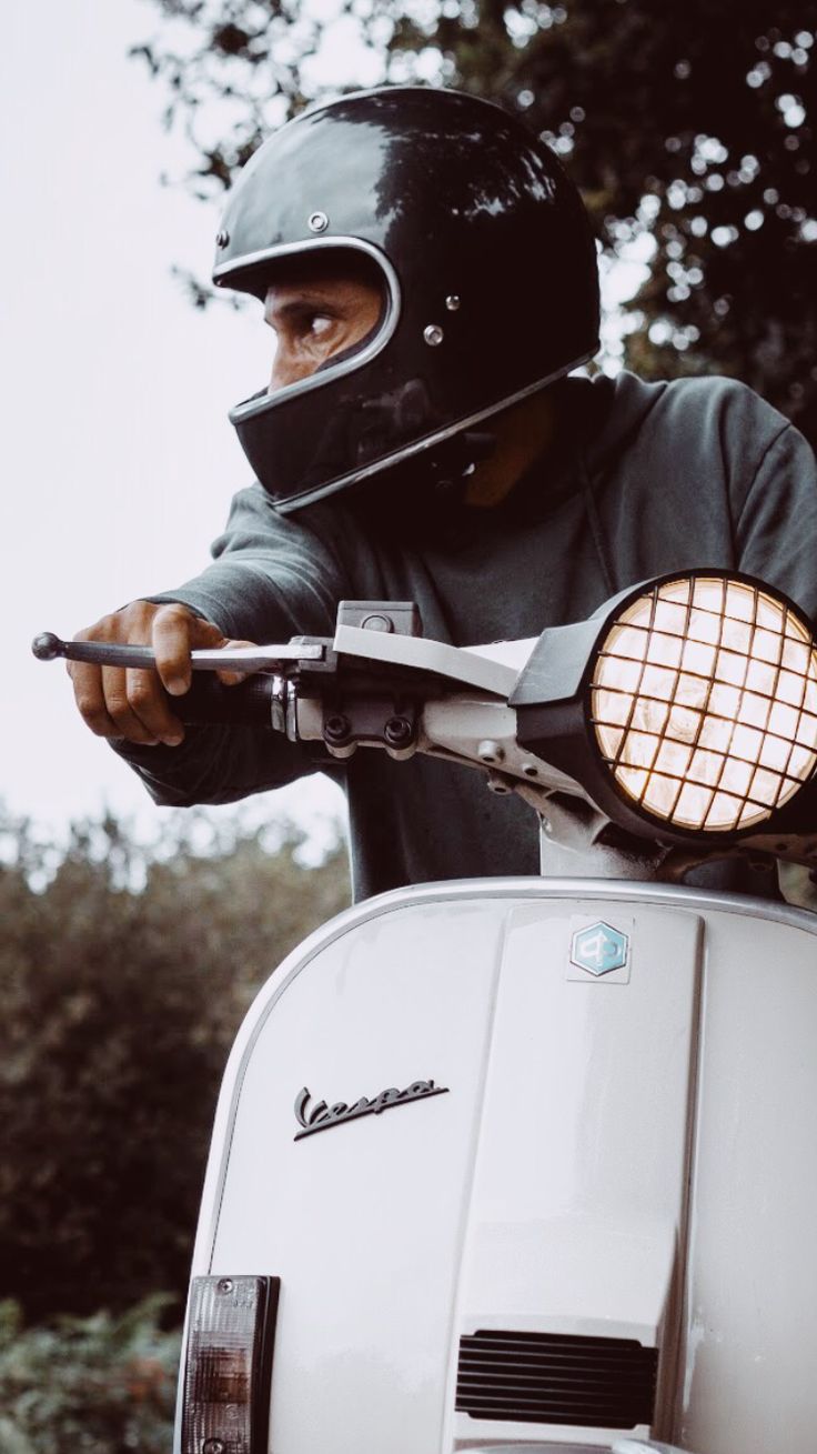 a man wearing a helmet on top of a scooter with a light attached to it