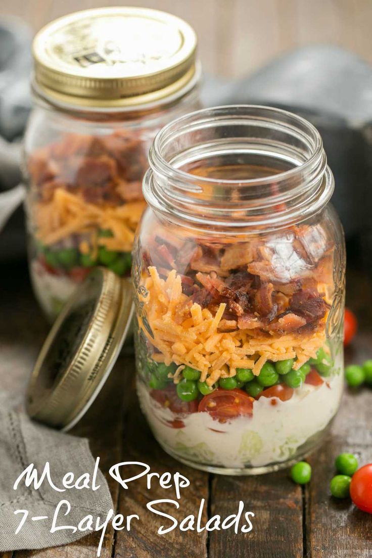 two mason jars filled with food sitting on top of a wooden table