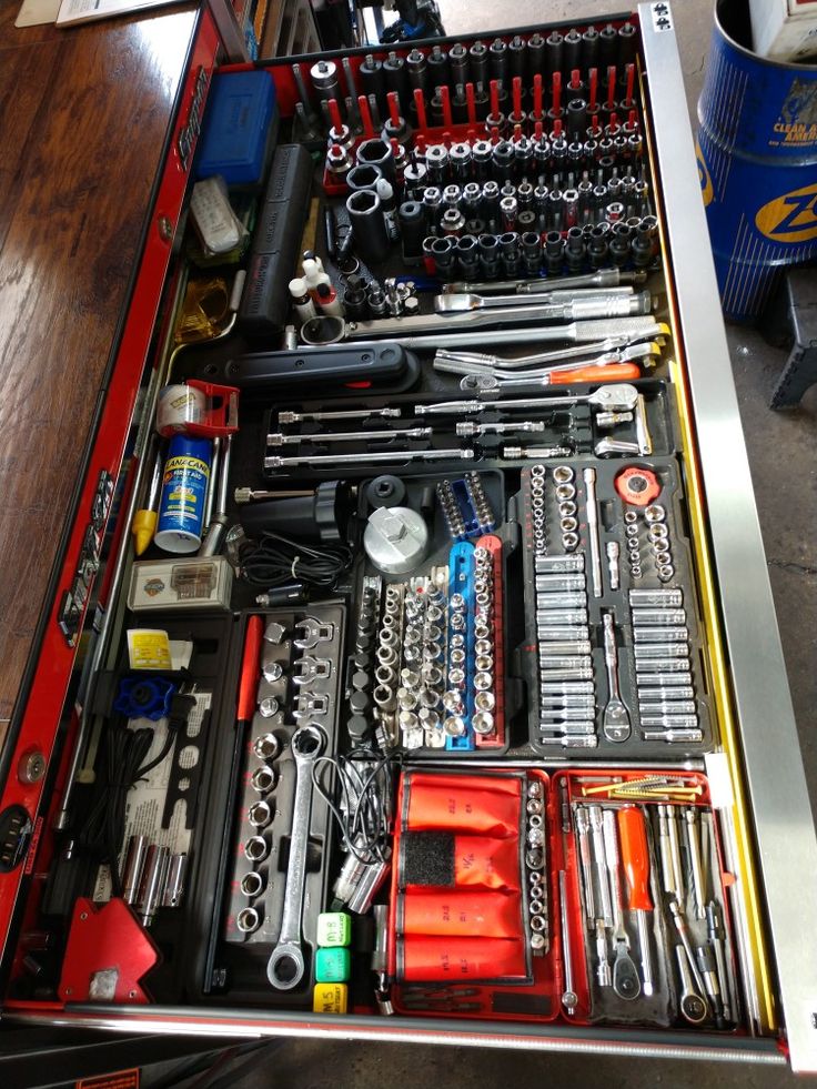 a drawer filled with tools and wrenches on top of a wooden table