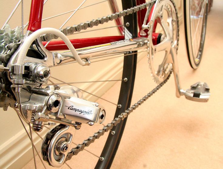 the front wheel of a red bicycle parked next to a wall with a door open