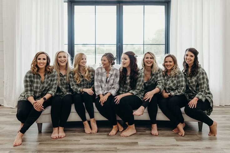 a group of women sitting next to each other on a couch in front of a window