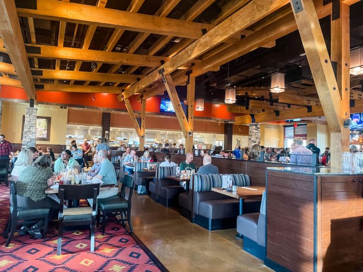 people sitting at tables in a restaurant with wooden ceilinging and beams on the ceiling