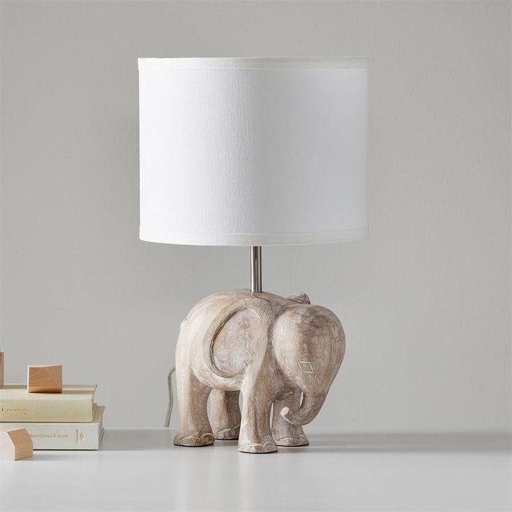 an elephant lamp sitting on top of a table next to a stack of books and a bookend