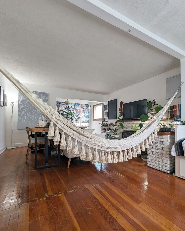 a hammock hanging in the middle of a living room with hardwood flooring