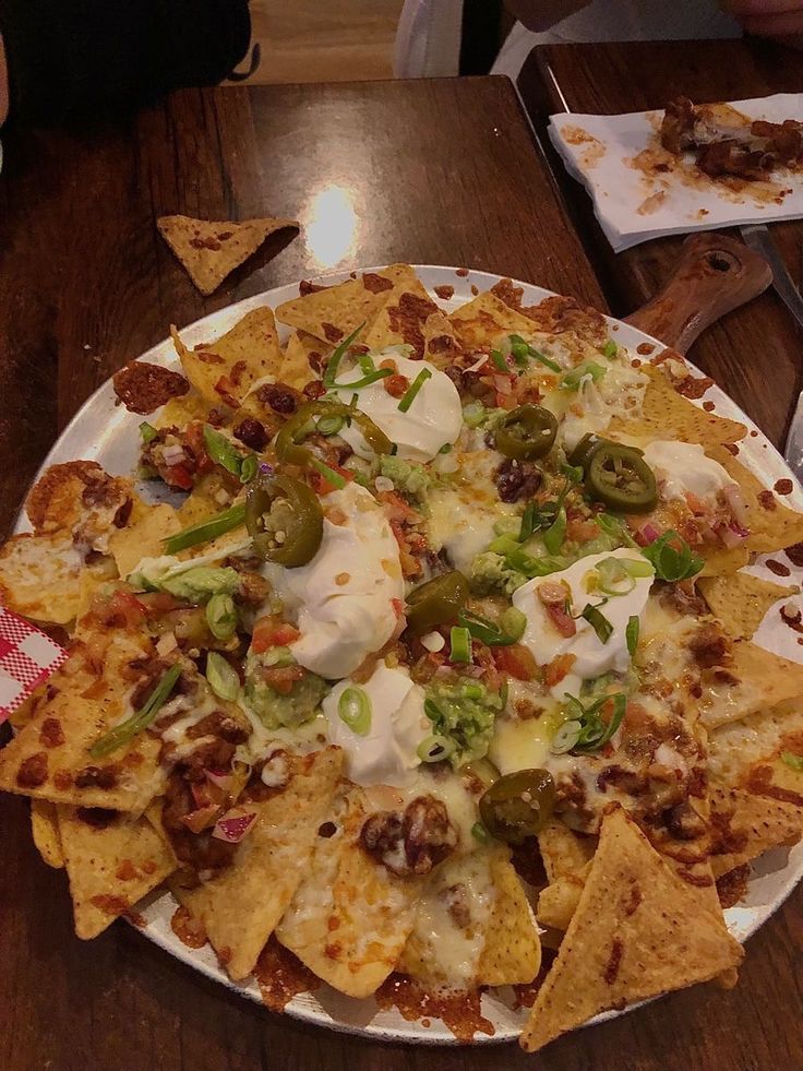 a plate full of nachos with cheese and toppings on it sitting on a table