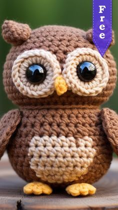 a crocheted owl sitting on top of a wooden table next to a purple tag