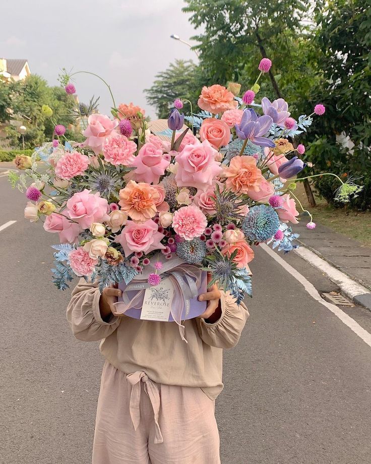 a person holding a bunch of flowers on their head in the middle of the road