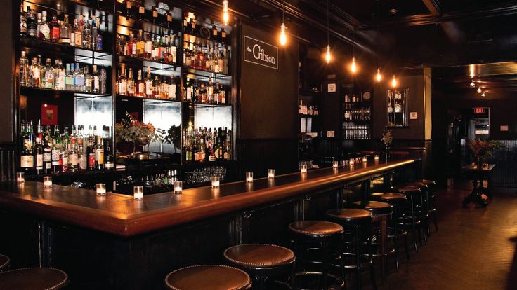 a dimly lit bar with lots of bottles on the shelves