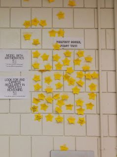 several yellow stars are pinned to the wall in front of a white brick wall with writing on it