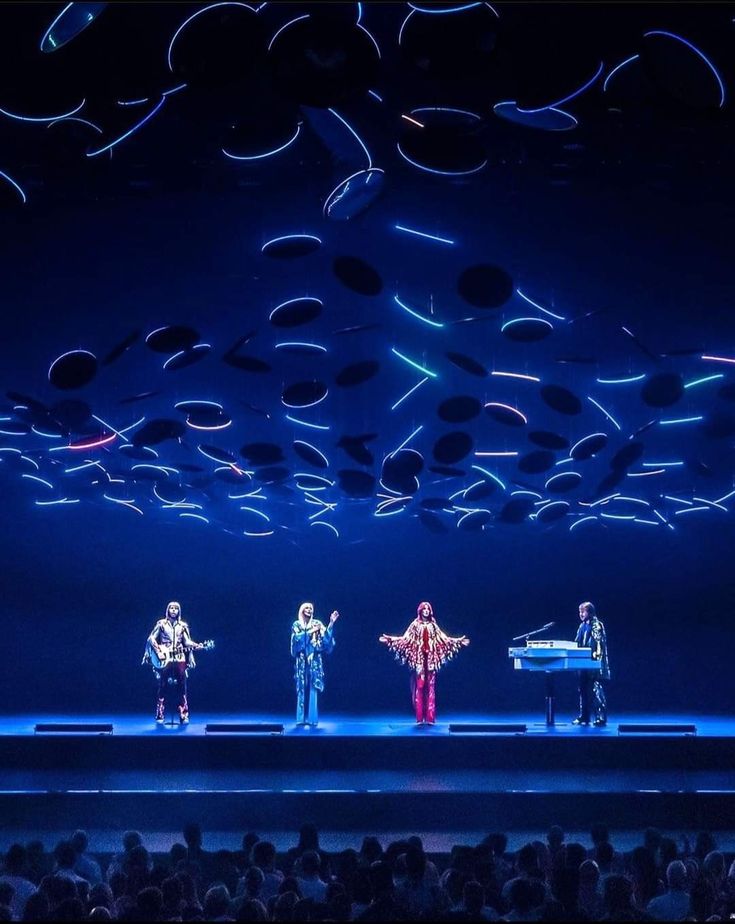 four people standing on stage in front of an audience