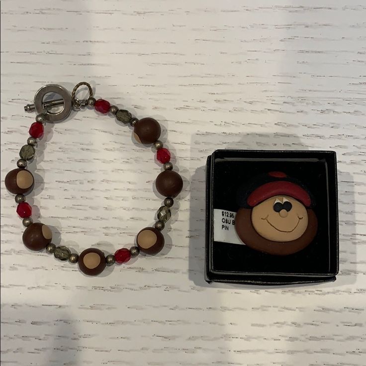 a bracelet with a monkey face on it next to a small box and keychain