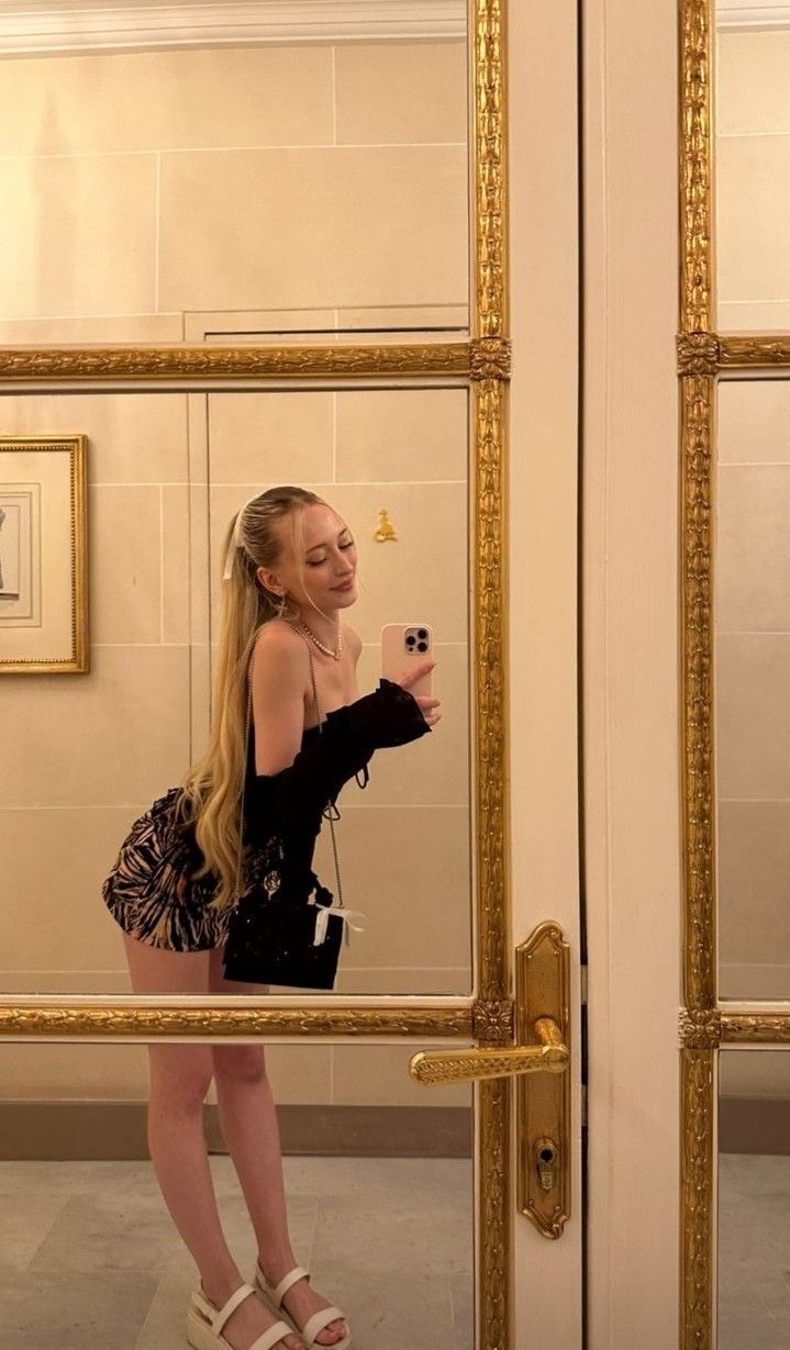 a woman taking a selfie in front of a mirror with her cell phone,