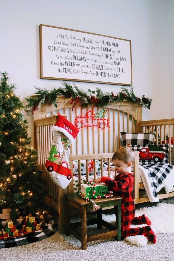 a toddler playing with christmas presents in his crib next to a christmas tree