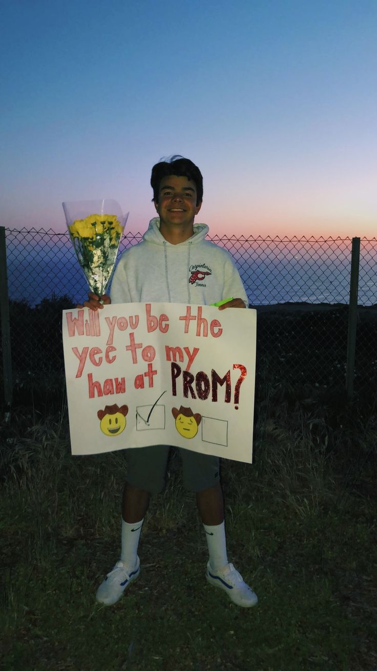 a man holding a sign that says will you be the yce to my how at prom?