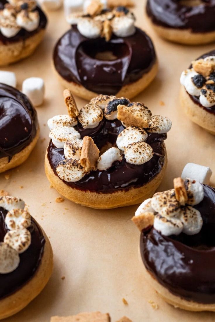 chocolate covered donuts topped with marshmallows and s'mores on a baking sheet