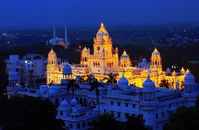 a large white building with lots of lights on it's sides and trees in the foreground