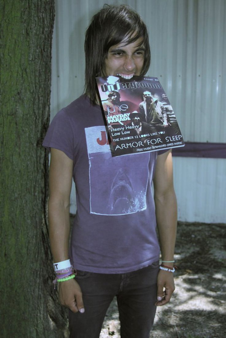 a man standing next to a tree holding up a book in front of his face