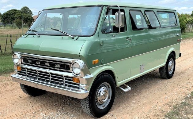 an old green van parked on a dirt road