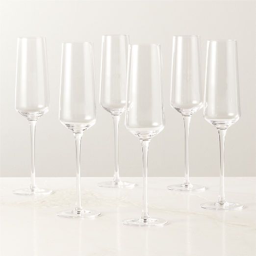 six wine glasses lined up on a white counter top with one empty glass in the middle