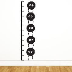 a growth chart wall sticker with black balls and eyes on it, in front of a white wall