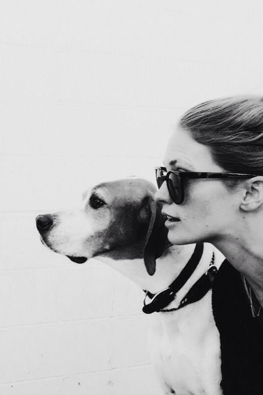 a woman in sunglasses kissing a dog on the nose with her head close to her face