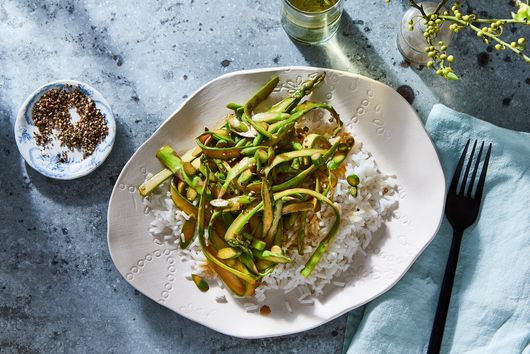 a plate with rice, asparagus and sauce on it next to a fork