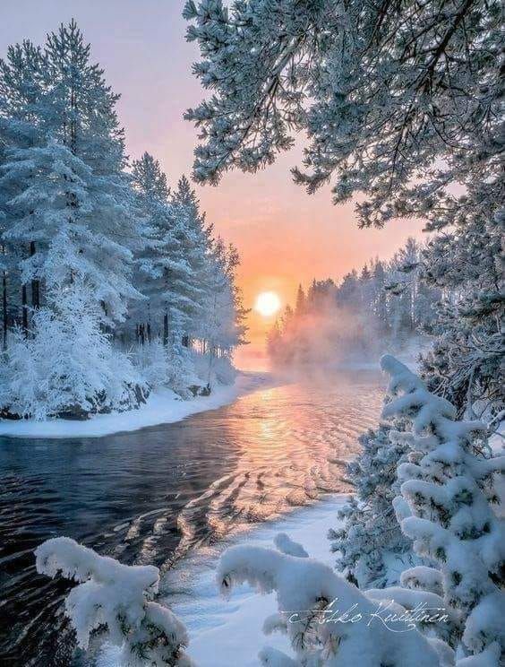 the sun is setting over a river surrounded by snow covered trees