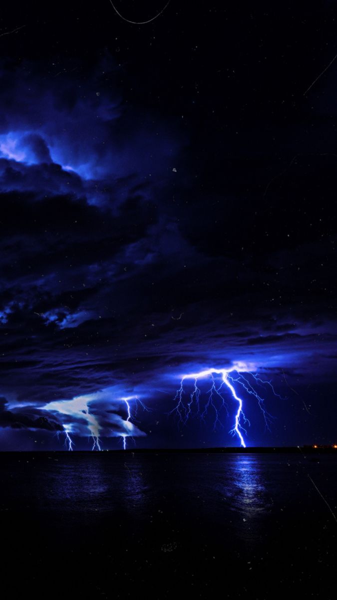 lightning strikes over the ocean at night time