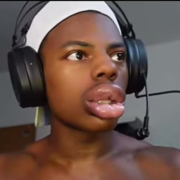 a shirtless man wearing headphones and making a face with his tongue sticking out