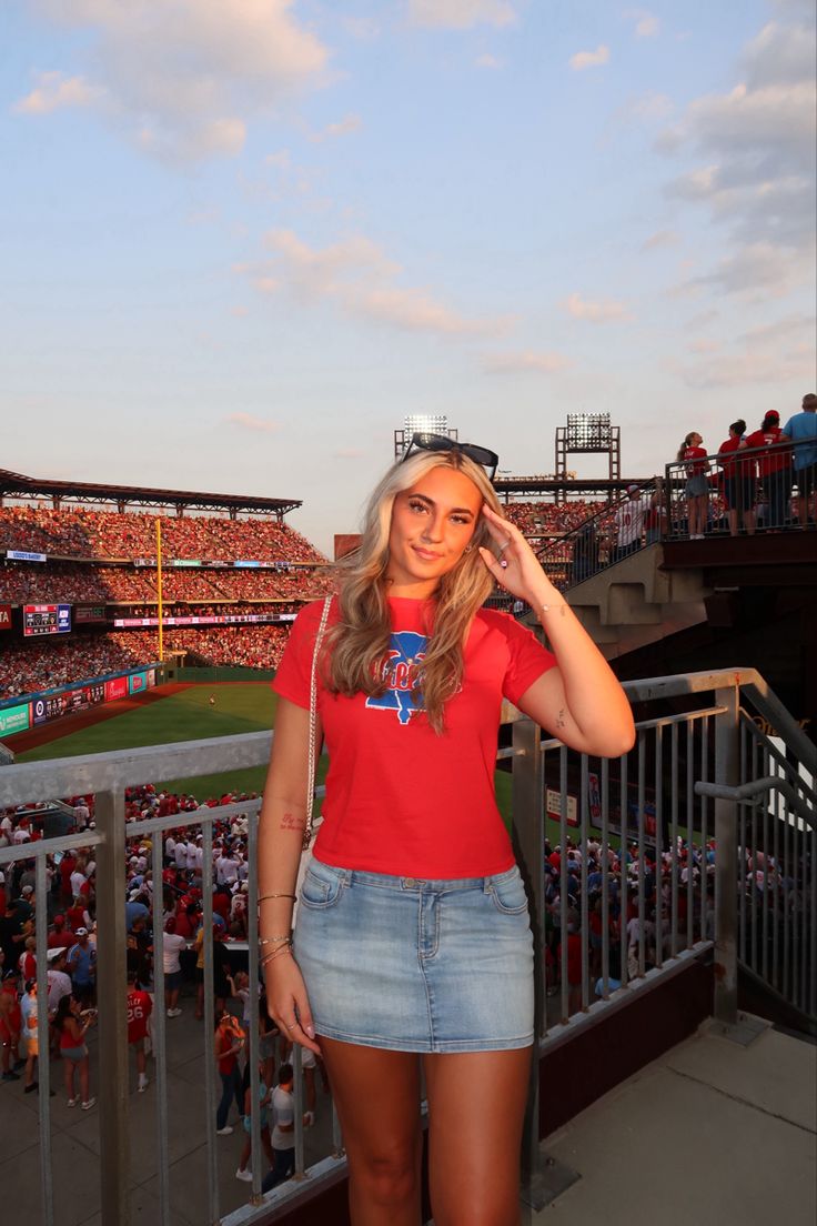 a beautiful young woman standing on top of a baseball field in front of a crowd