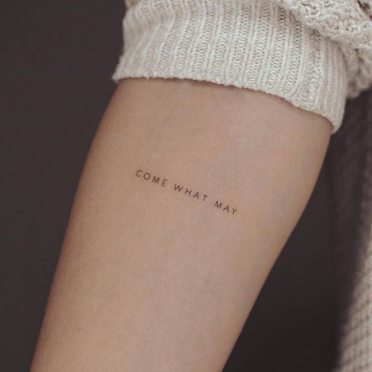 a woman's arm with the words, come what may written on it in cursive font