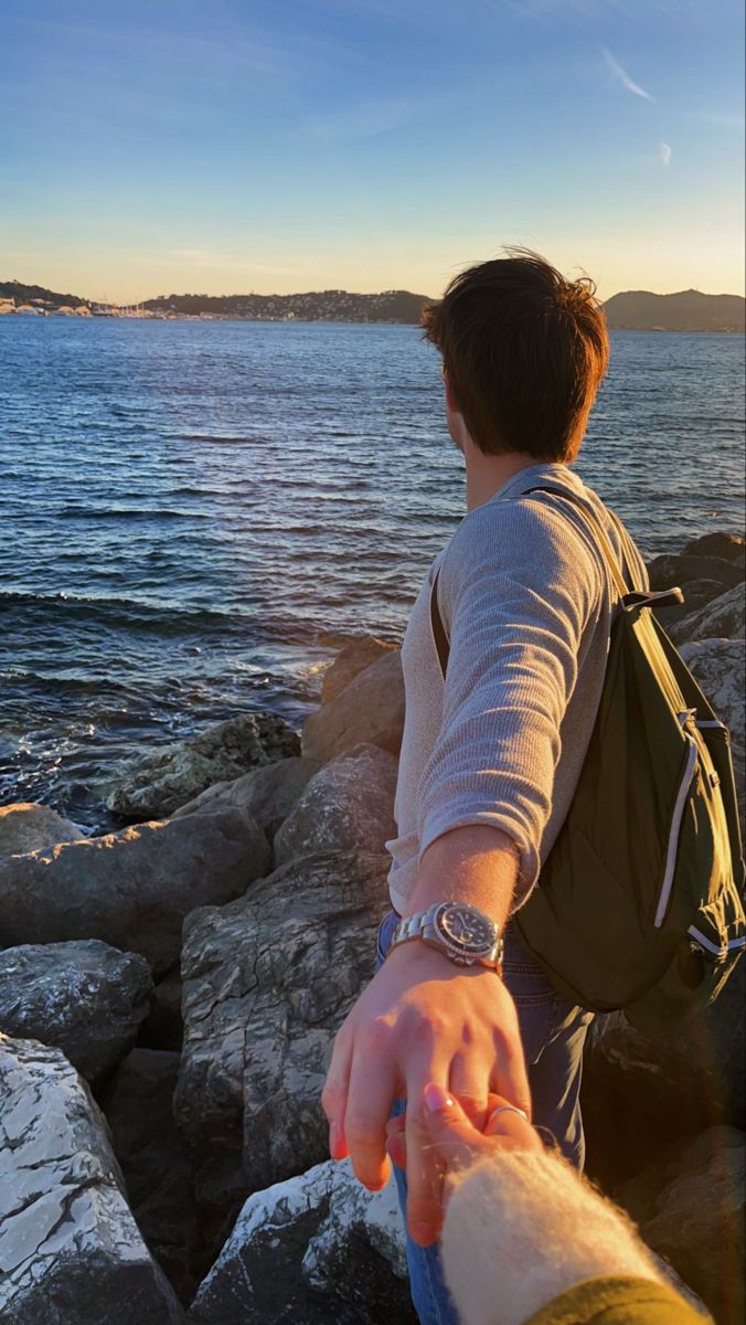 two people holding hands near the water