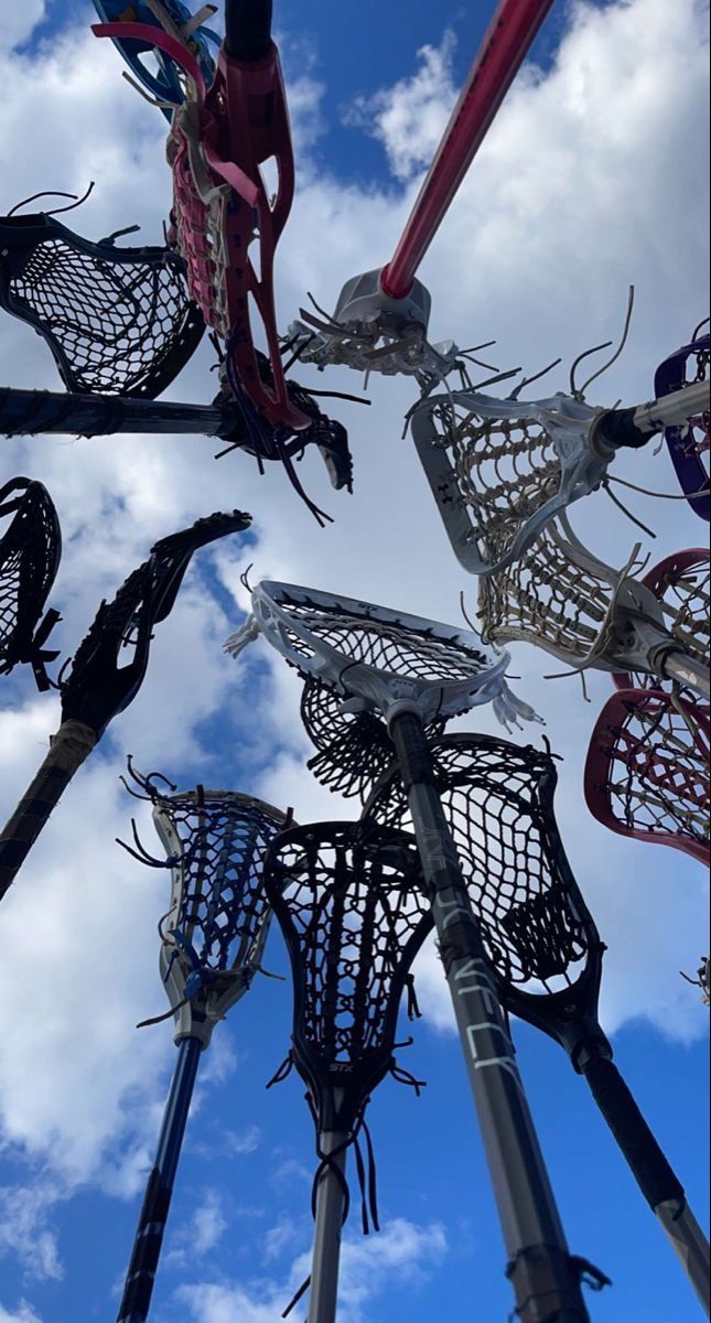 several lacrosse goalies are in the air against a blue sky with clouds behind them