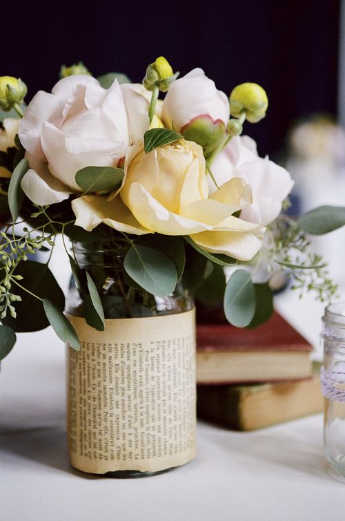 a vase filled with flowers sitting on top of a table next to two book pages