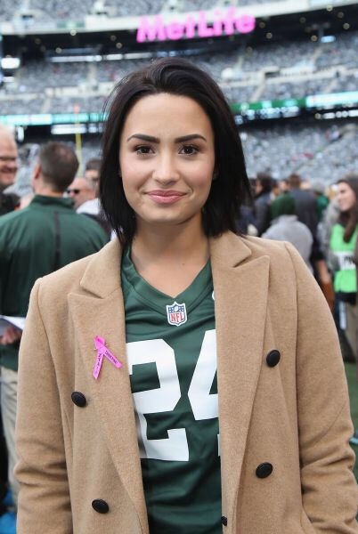 a woman standing in front of a crowd at a football game wearing a green and white shirt