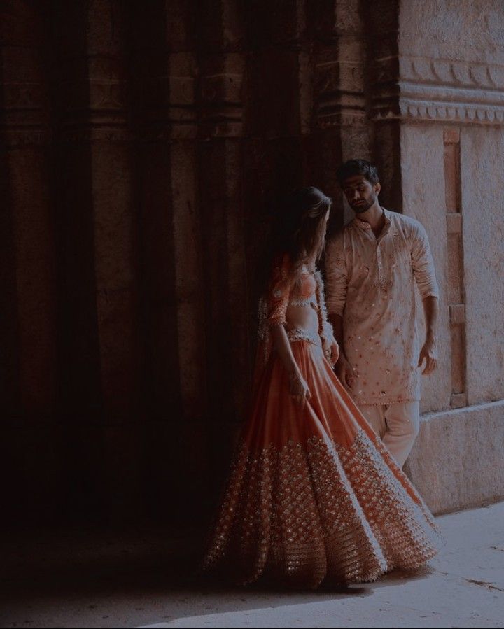 a man and woman standing next to each other in front of a stone building with columns