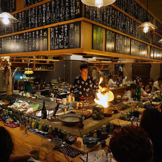 a group of people sitting around a table with food on it in a room full of shelves