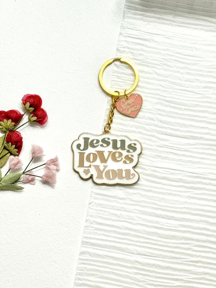 a keychain with the words jesus loves you on it next to some flowers