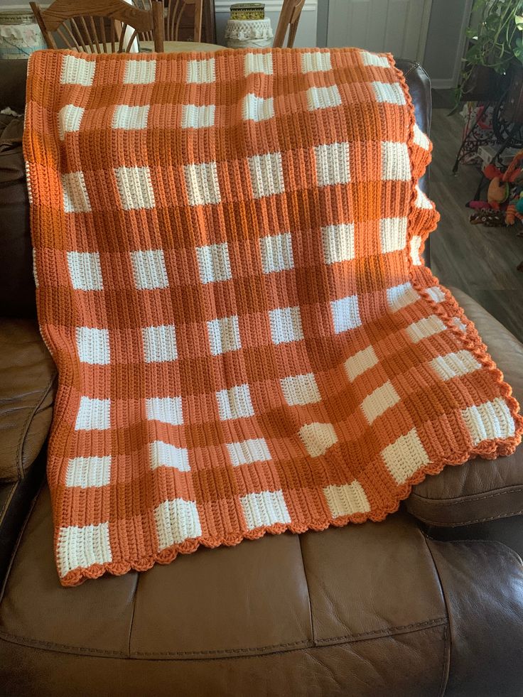 an orange and white blanket sitting on top of a couch