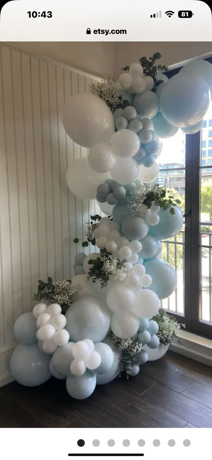 balloons and greenery are arranged in the shape of an arch for a balloon display