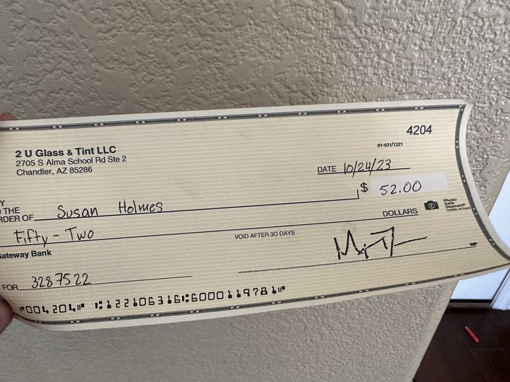 a person holding up a check for $ 2, 500