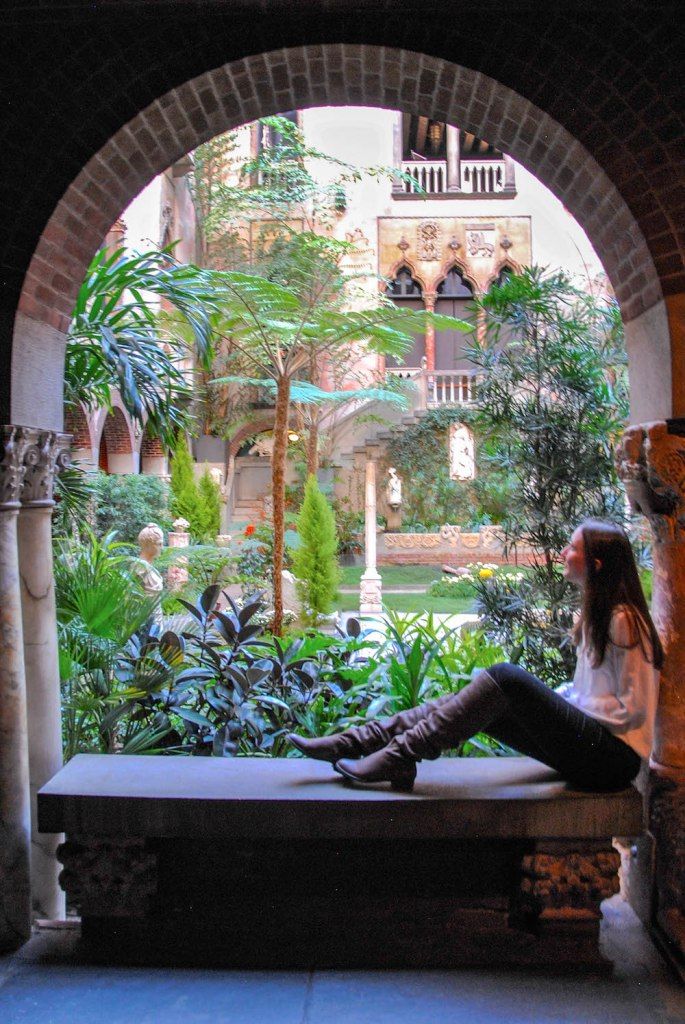 a woman sitting on top of a bench in front of a window next to plants