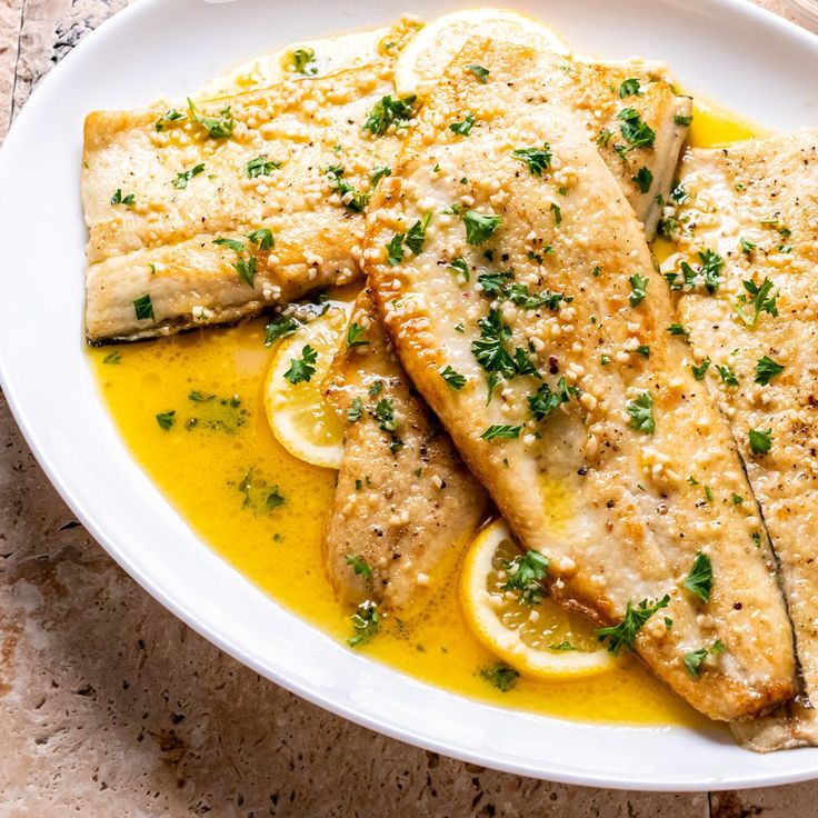 two fish fillets with lemon sauce on a white plate