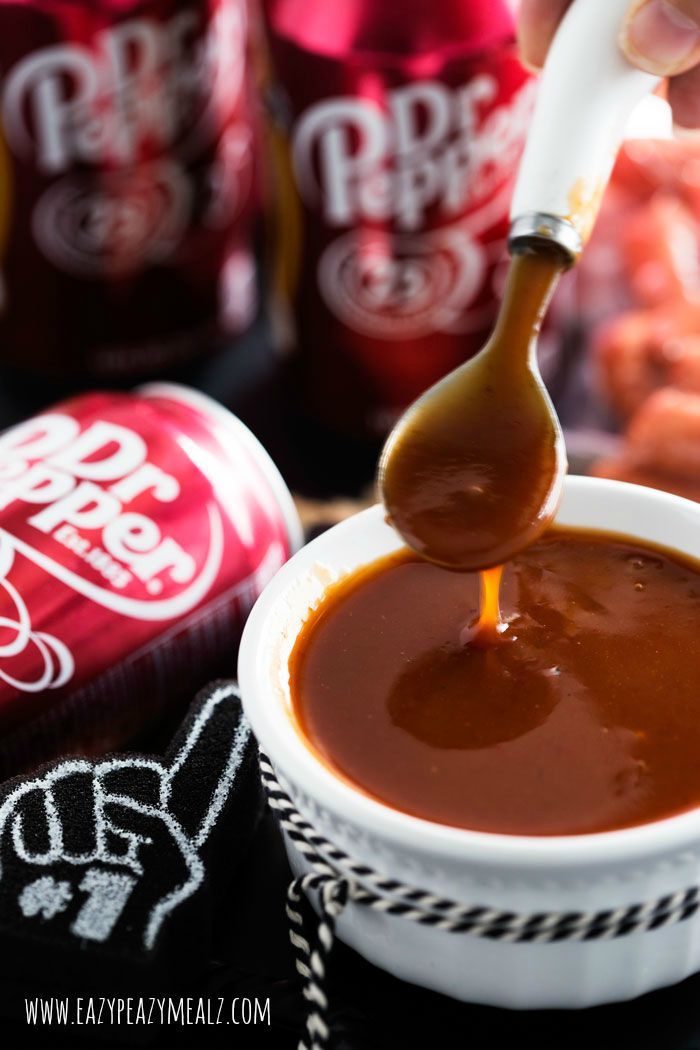 a spoon full of caramel sauce being poured into a cup with coca - cola in the background