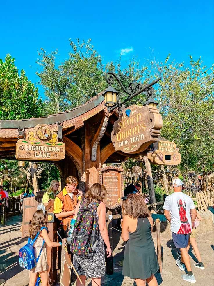 people are standing in front of the entrance to an amusement park with wooden structures and signs