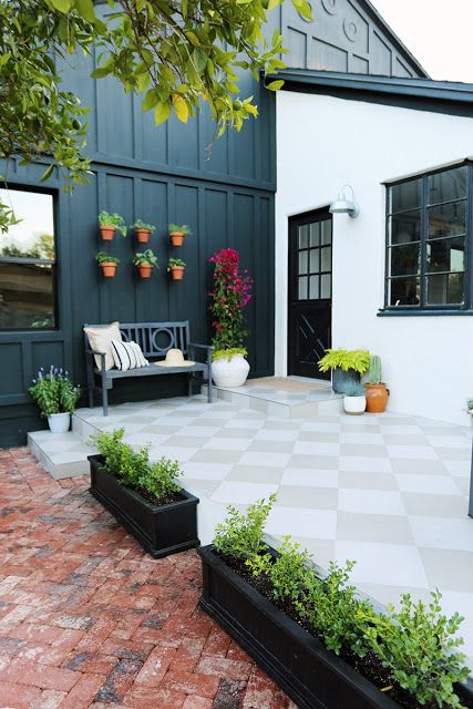 an outdoor patio with potted plants on the side and a bench in the middle